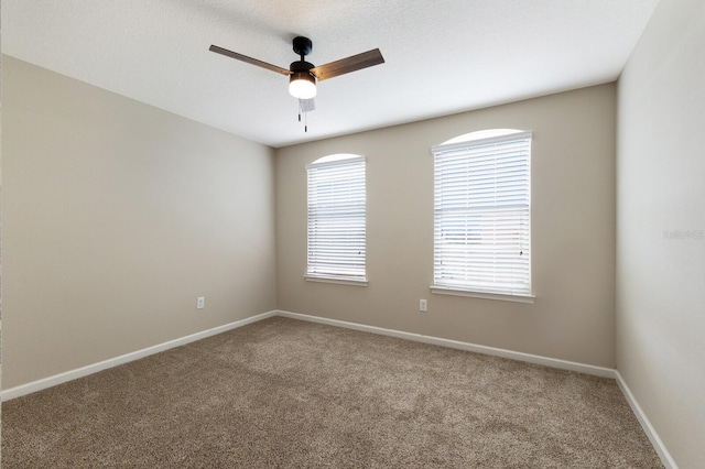 carpeted empty room featuring ceiling fan and a wealth of natural light