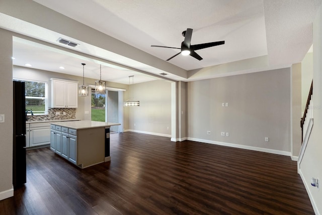 kitchen with a kitchen island, decorative light fixtures, white cabinets, decorative backsplash, and black fridge