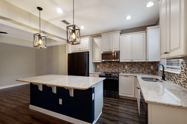 kitchen featuring range with electric stovetop, a kitchen island, pendant lighting, sink, and black fridge