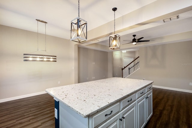 kitchen with hanging light fixtures, dark hardwood / wood-style flooring, a kitchen island, ceiling fan, and light stone countertops