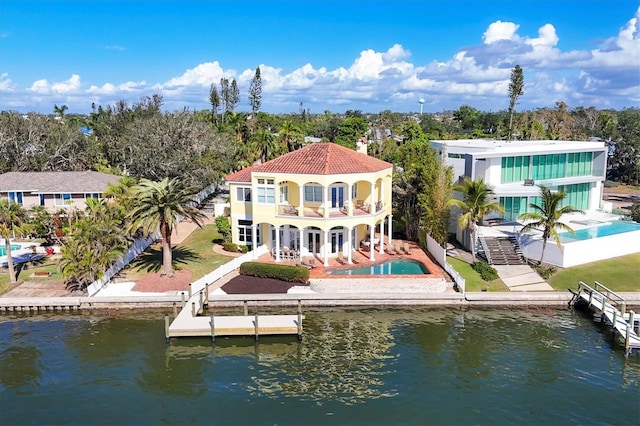 rear view of house with a patio, a balcony, and a water view