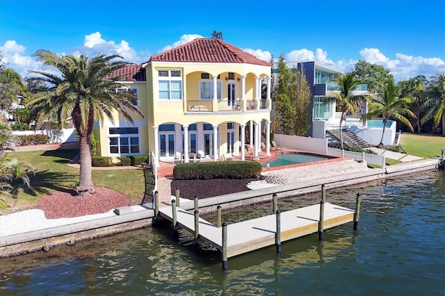 rear view of property featuring a lawn, a balcony, a patio, and a water view