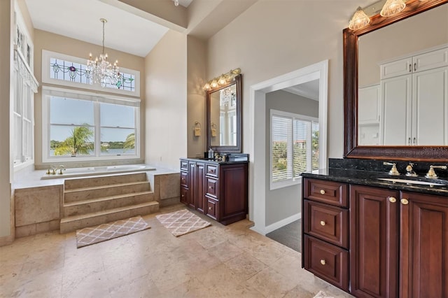 bathroom featuring vanity, a relaxing tiled tub, and an inviting chandelier