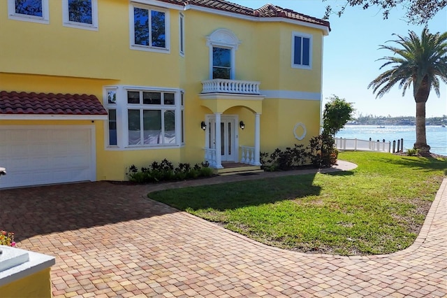 mediterranean / spanish-style house with a garage, a water view, a balcony, and a front yard