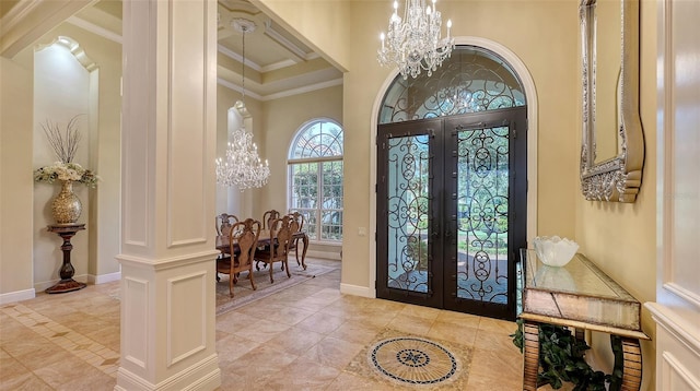 entrance foyer with a high ceiling, an inviting chandelier, french doors, ornamental molding, and decorative columns