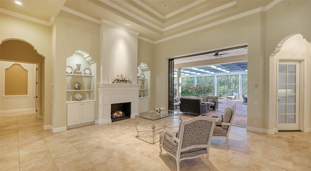 living room with ceiling fan, built in features, ornamental molding, and a towering ceiling