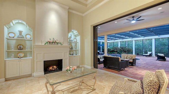 living room featuring ceiling fan, a large fireplace, built in features, and ornamental molding