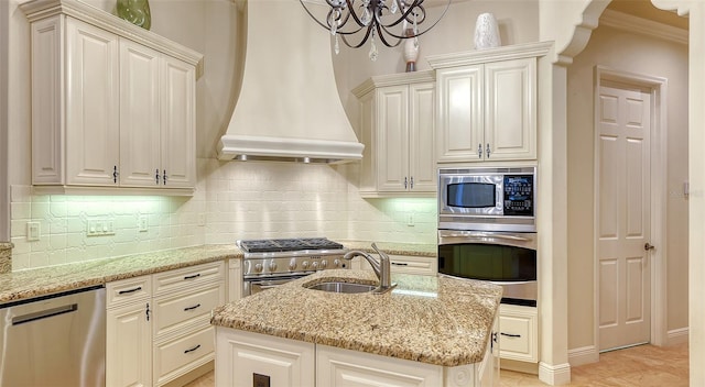 kitchen with premium range hood, a kitchen island with sink, sink, light stone countertops, and stainless steel appliances