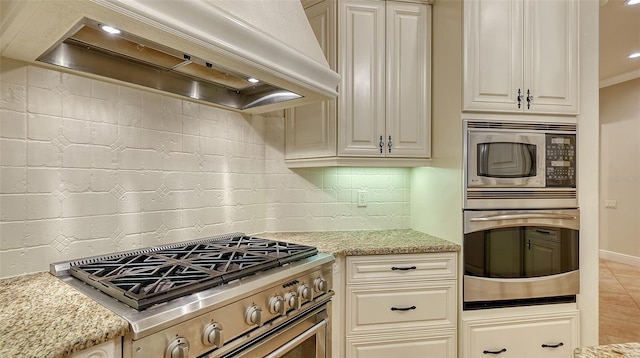 kitchen with premium range hood, light stone counters, and stainless steel appliances