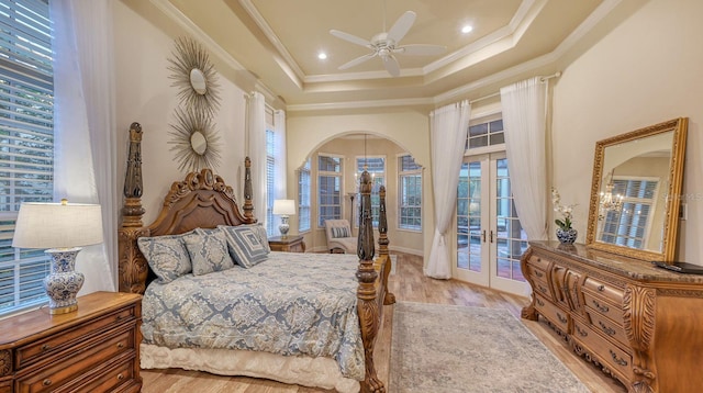 bedroom featuring access to exterior, ceiling fan, french doors, light hardwood / wood-style floors, and a tray ceiling