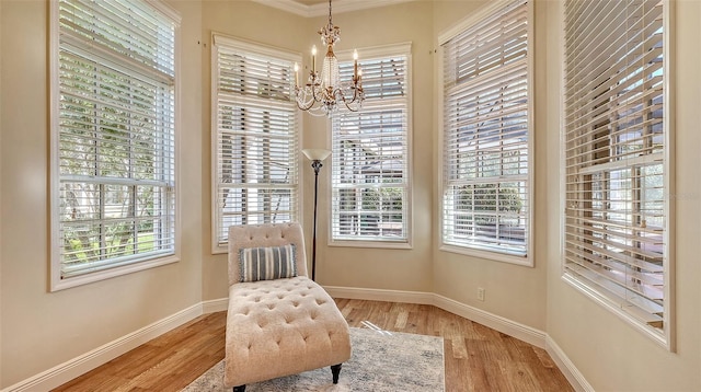 living area featuring a notable chandelier, light wood-type flooring, and ornamental molding