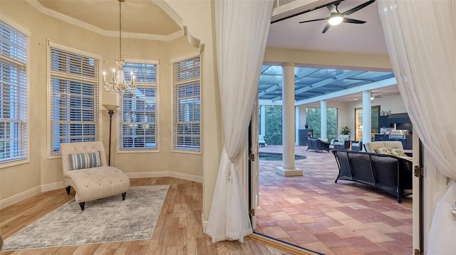 entryway featuring ceiling fan with notable chandelier, wood-type flooring, and ornamental molding