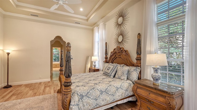 bedroom with multiple windows, a raised ceiling, ceiling fan, and crown molding