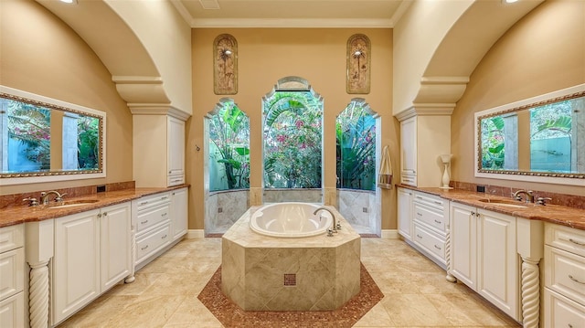 bathroom featuring vanity, a relaxing tiled tub, and a healthy amount of sunlight