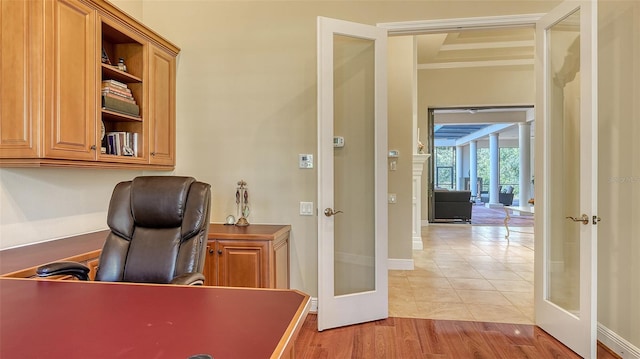 office with light hardwood / wood-style flooring and french doors