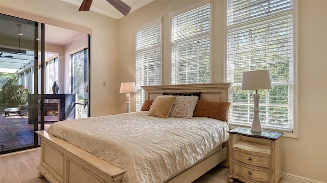 bedroom featuring access to exterior, light wood-type flooring, multiple windows, and ceiling fan