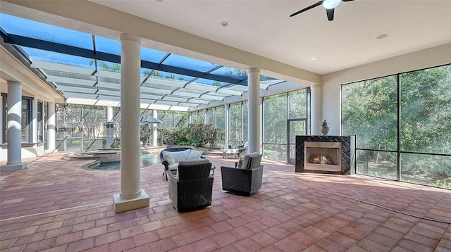 unfurnished sunroom featuring ceiling fan and a fireplace