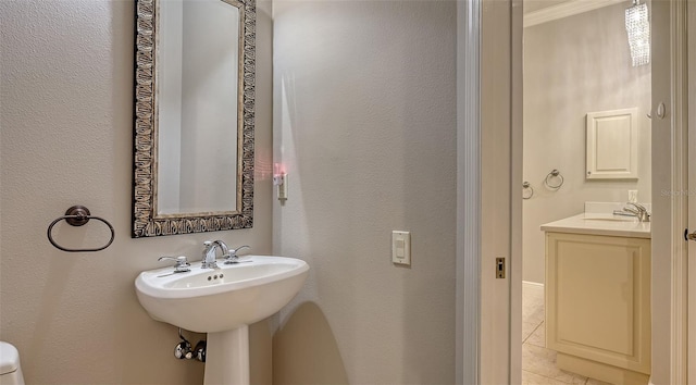 bathroom featuring tile patterned floors, crown molding, and sink