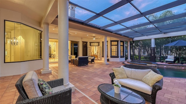 patio terrace at dusk featuring outdoor lounge area, glass enclosure, ceiling fan, and a swimming pool with hot tub