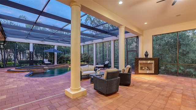 view of patio featuring a lanai, ceiling fan, an outdoor hangout area, and a pool with hot tub