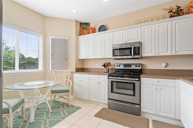 kitchen featuring white cabinets, light tile patterned flooring, and appliances with stainless steel finishes