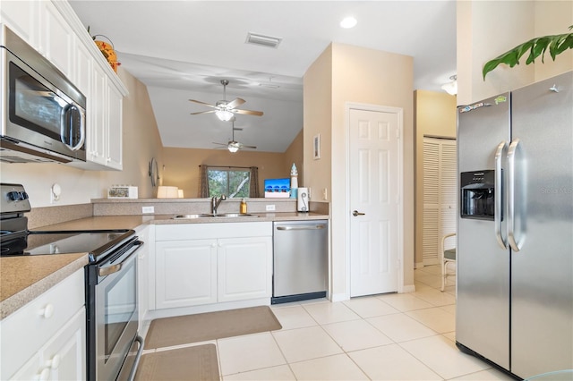 kitchen featuring lofted ceiling, sink, light tile patterned floors, white cabinetry, and stainless steel appliances