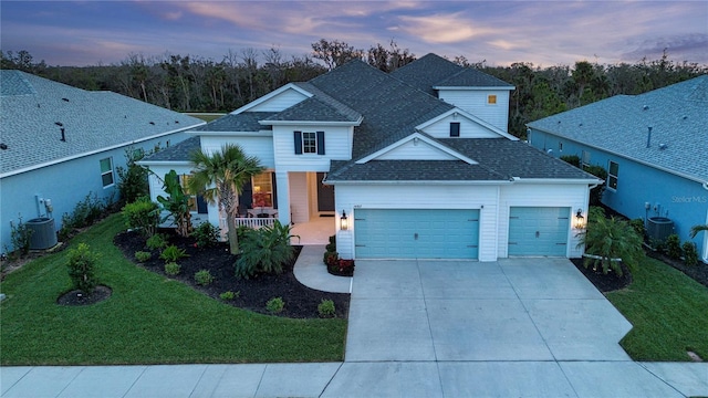 view of front of property featuring a yard, covered porch, central AC unit, and a garage