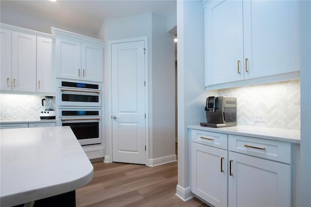 kitchen featuring backsplash, white cabinetry, light hardwood / wood-style flooring, and double wall oven