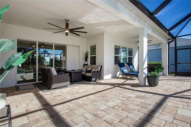 view of patio featuring an outdoor living space, glass enclosure, and ceiling fan