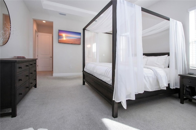 carpeted bedroom featuring a tray ceiling and crown molding