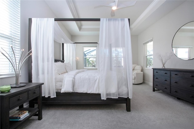 bedroom with ceiling fan, a raised ceiling, light carpet, and multiple windows