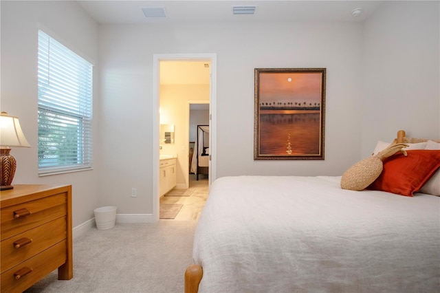 bedroom featuring light carpet and ensuite bath