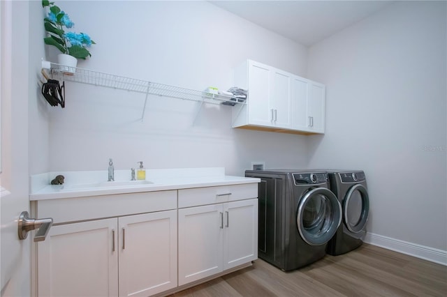 laundry room featuring washer and clothes dryer, sink, hardwood / wood-style floors, and cabinets