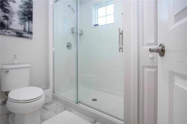 bathroom featuring toilet and a shower with door