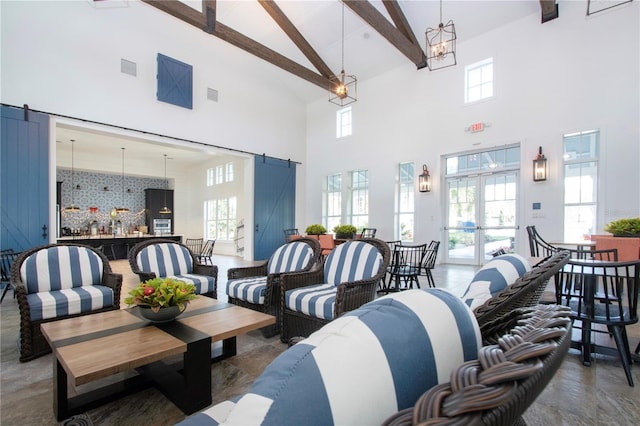 interior space with a barn door, french doors, beamed ceiling, and high vaulted ceiling