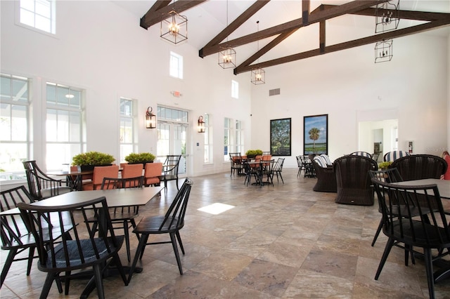 dining space featuring beamed ceiling, a towering ceiling, and an inviting chandelier