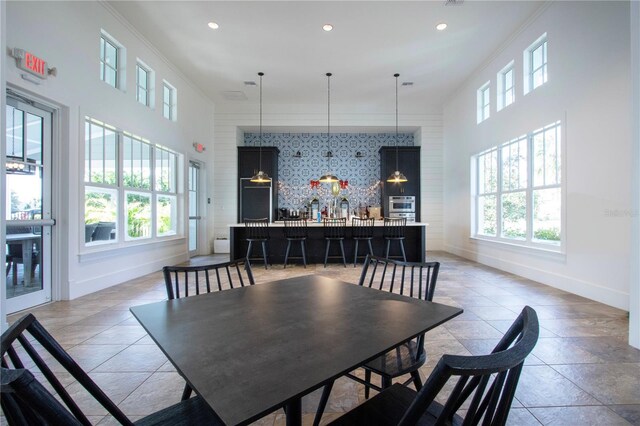 dining space featuring bar, a wealth of natural light, and ornamental molding