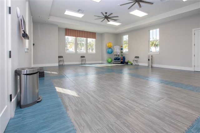 exercise room with a raised ceiling and ceiling fan