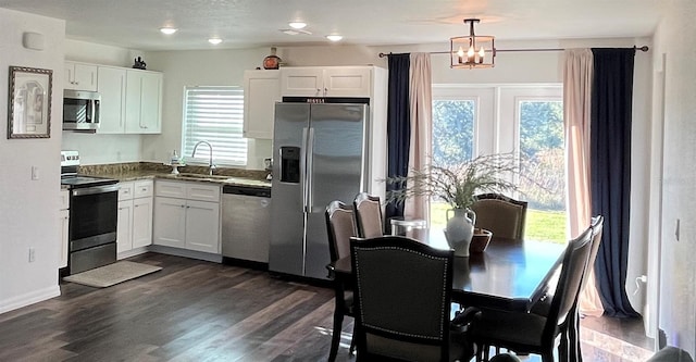 kitchen featuring decorative light fixtures, white cabinetry, sink, and appliances with stainless steel finishes