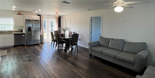 living room featuring dark hardwood / wood-style flooring, a textured ceiling, ceiling fan, and sink