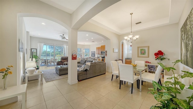 dining room featuring ceiling fan with notable chandelier, a raised ceiling, and light tile patterned floors