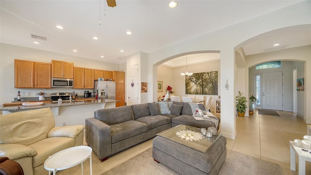 tiled living room with sink and ceiling fan with notable chandelier