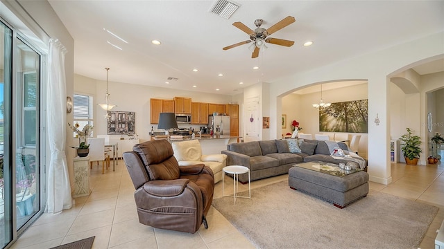 tiled living room featuring ceiling fan with notable chandelier