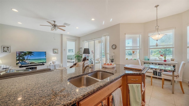 kitchen featuring sink, hanging light fixtures, ceiling fan, dark stone countertops, and light tile patterned floors