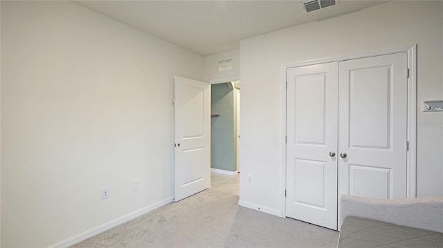 unfurnished bedroom featuring light carpet and a closet