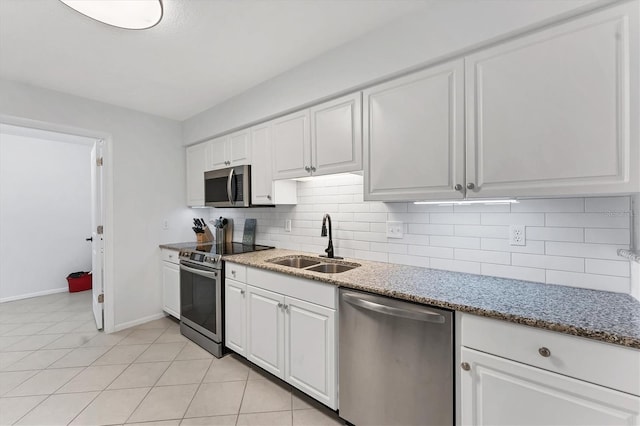 kitchen featuring sink, light tile patterned floors, appliances with stainless steel finishes, light stone counters, and white cabinetry