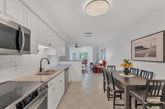 kitchen featuring decorative backsplash, light stone counters, stainless steel appliances, sink, and white cabinets