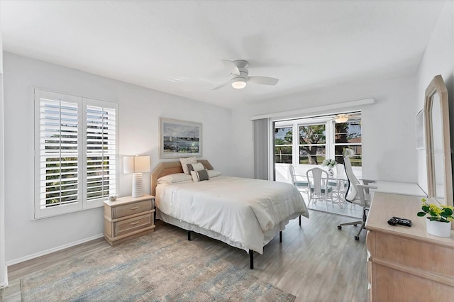 bedroom with multiple windows, wood-type flooring, access to outside, and ceiling fan