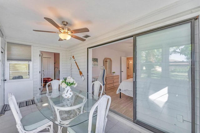 tiled dining space featuring ceiling fan and ornamental molding