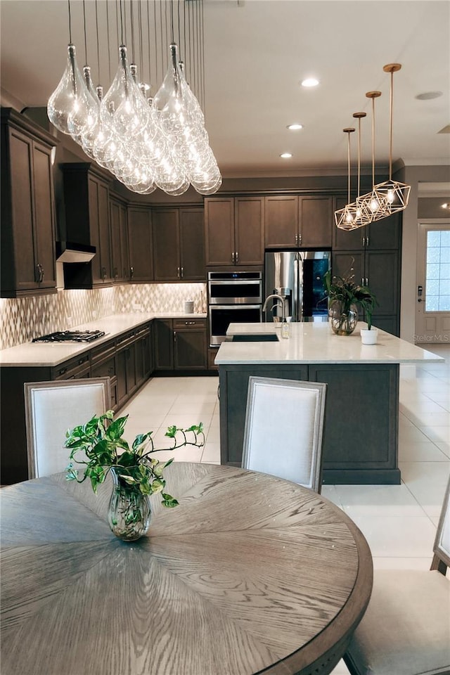 kitchen featuring a center island with sink, dark brown cabinets, light tile patterned floors, and stainless steel appliances